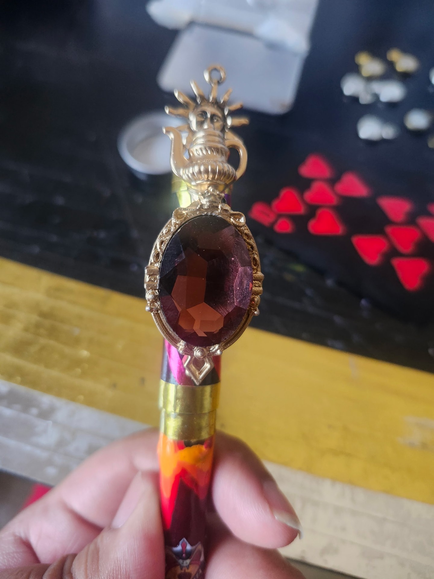 Hand-painted gem holder with sun and teapot topper, deep red gem