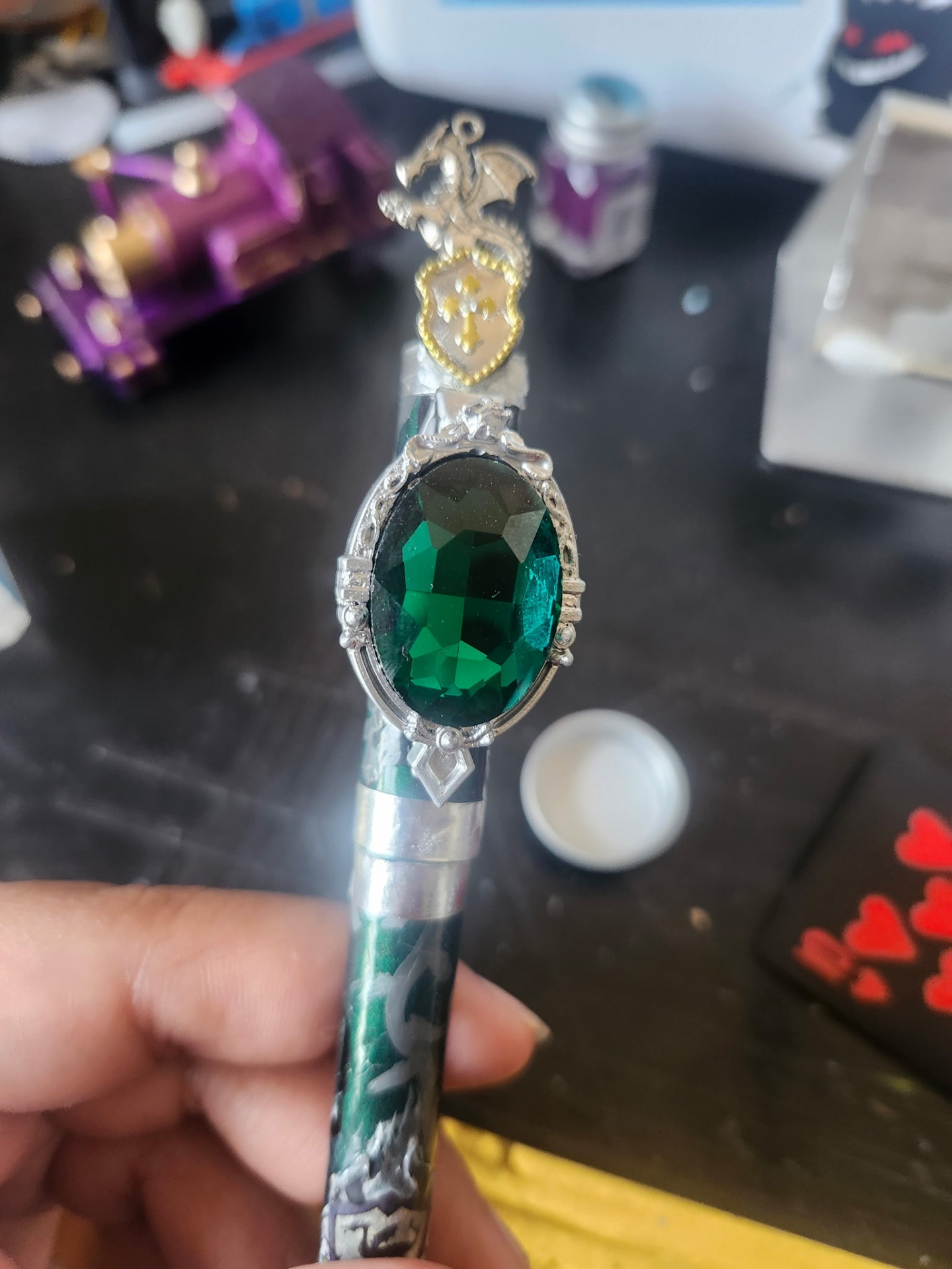 Hand-painted gem holder with dragon-and-shield topper, emerald gem